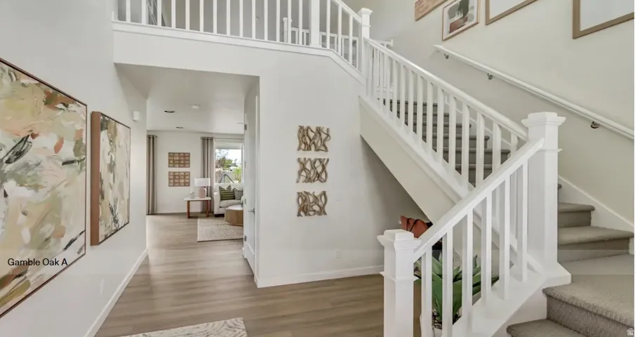 Two-story foyer with wood-finish flooring, a white spindle staircase, and an upper landing with matching white railings. This home is To Be Built and pictures are of a previous home