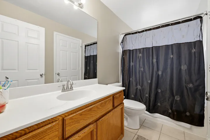 Bathroom featuring a vanity with wood-finish cabinetry and a white countertop, an undermount sink, and a chrome faucet