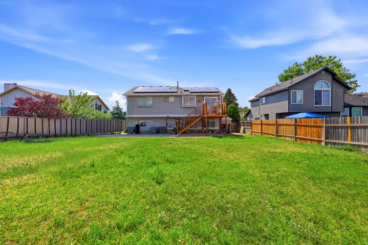 Spacious backyard with a wooden fence, large grassy area, and a two-story deck