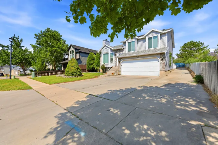 Exterior featuring light grey siding, stone accents, and a white garage door