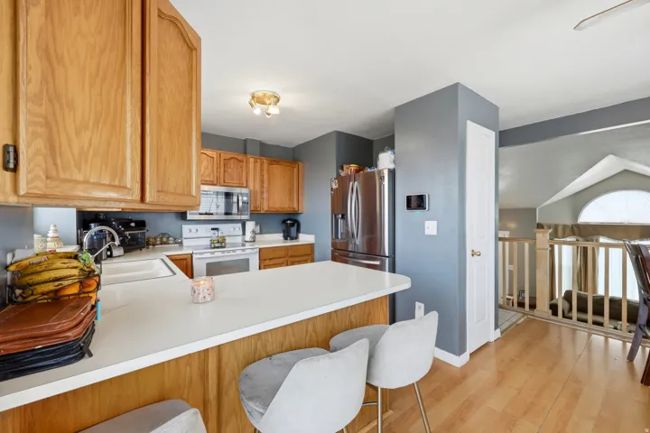 Kitchen featuring wood cabinetry, stainless steel appliances, white countertops, and wood-finish flooring
