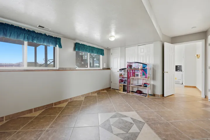Spacious room featuring tile flooring with a decorative inlay, multiple windows, and white interior doors