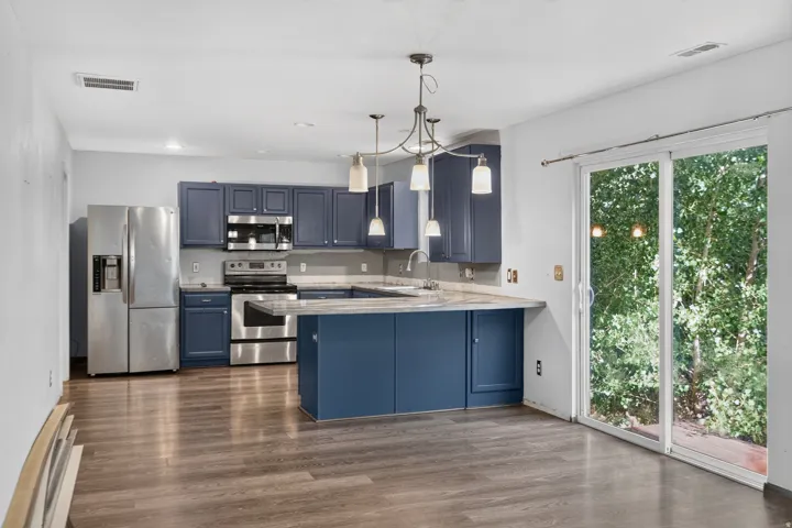 Contemporary kitchen featuring blue cabinetry, stainless steel appliances, and wood-finish flooring