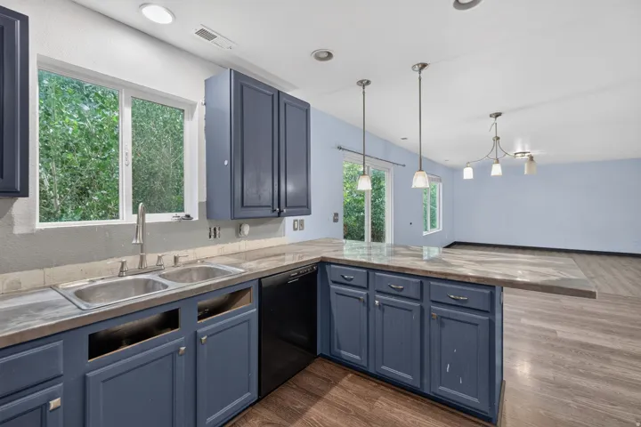 Kitchen featuring blue cabinetry, a stainless steel double basin sink, and a black dishwasher