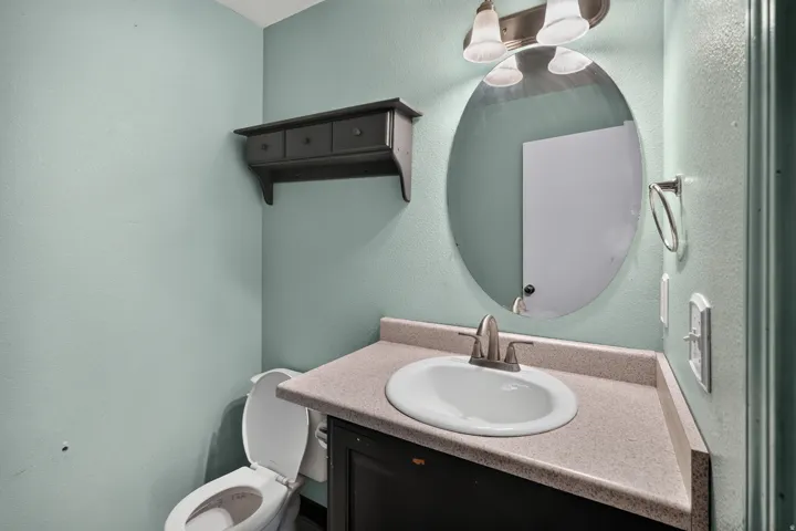 Compact bathroom featuring a white oval sink, brushed nickel faucet, and a light-colored countertop