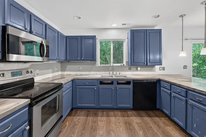 Kitchen featuring blue cabinetry, wood-finish flooring, stainless steel appliances including a microwave and range, and a double basin sink