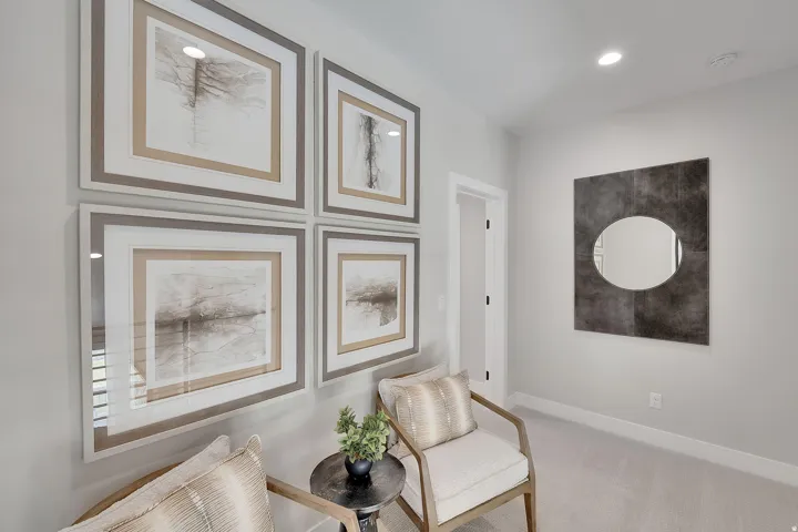 Carpeted interior area featuring a gallery wall with four framed art pieces, recessed lighting, and a square-framed oval mirror