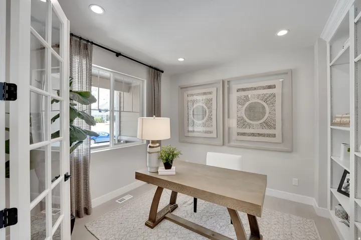 French doors opening to a versatile room featuring a window with patterned drapes, built-in shelving, and recessed lighting