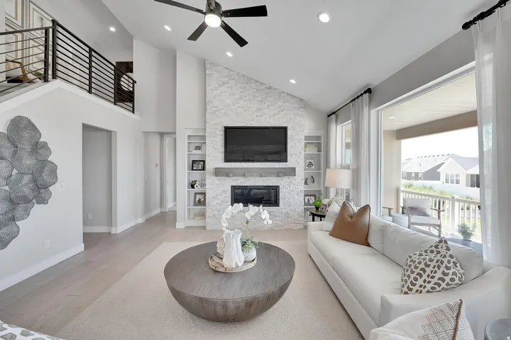 Vaulted living area featuring a floor-to-ceiling stacked stone fireplace, an integrated media center, and built-in shelving