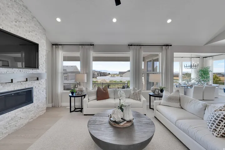 Spacious living area featuring a stacked stone fireplace with a built-in electric insert, light wood-finish flooring, recessed lighting, and multiple large windows