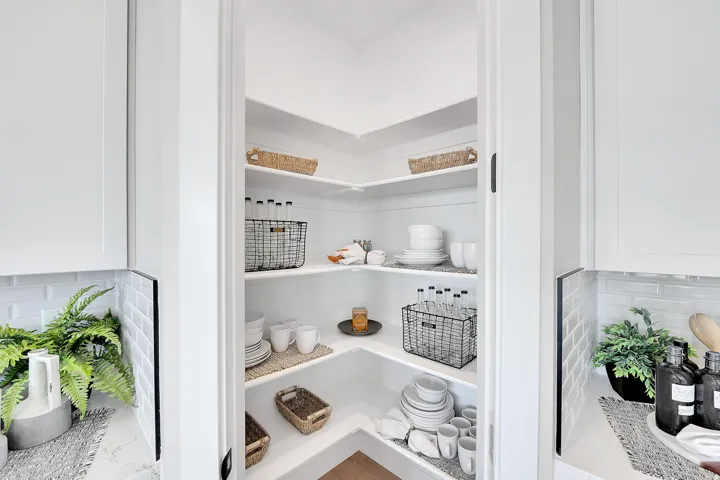 Walk-in pantry featuring abundant white shelving, white walls, and wood-finish flooring