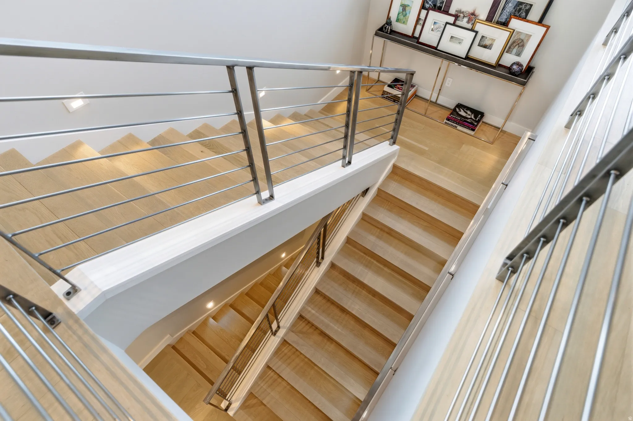 Contemporary multi-level staircase featuring light wood steps and stainless steel cable railings