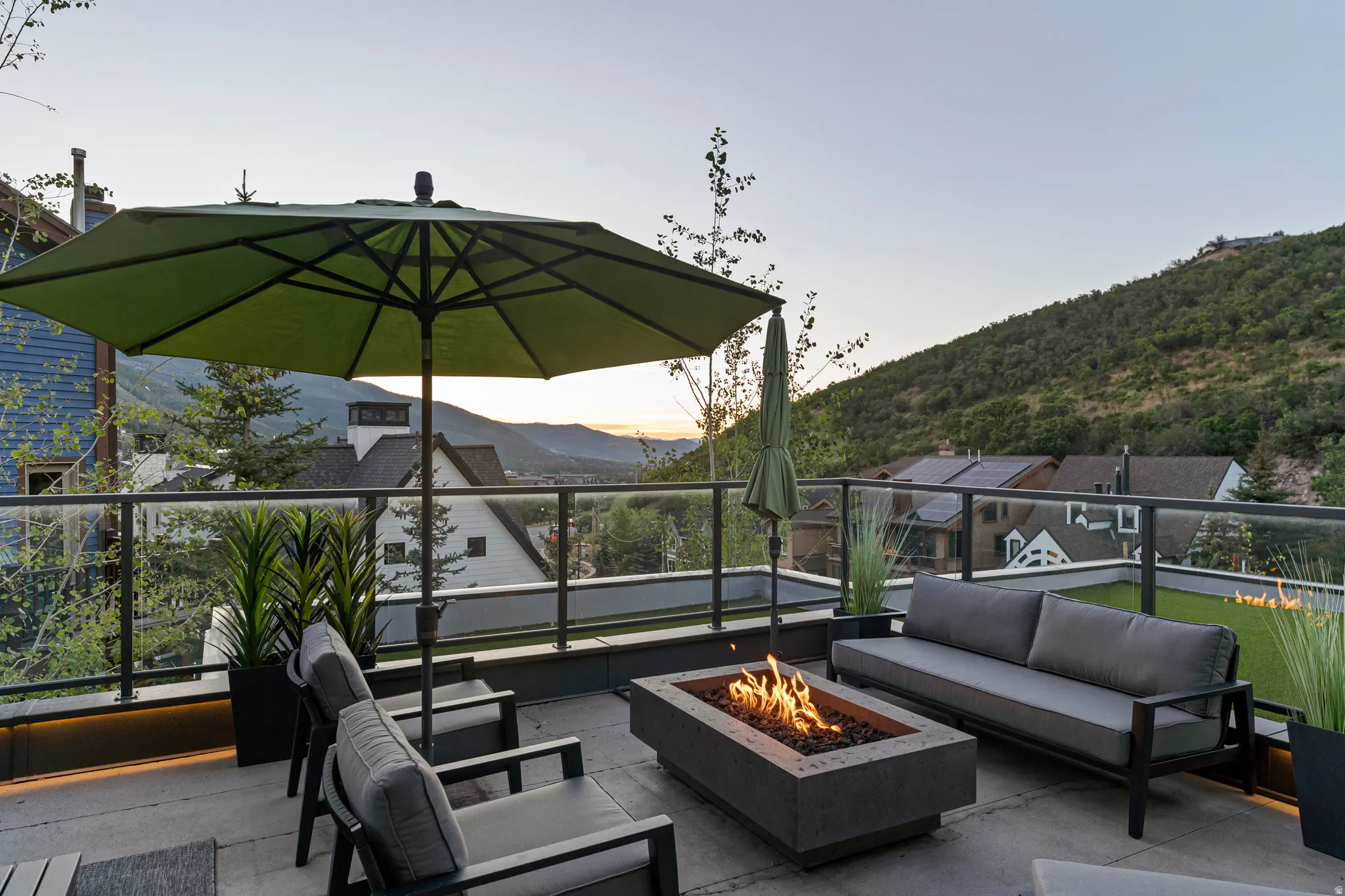 Expansive outdoor patio featuring a built-in fire pit, glass panel railing, and integrated planters