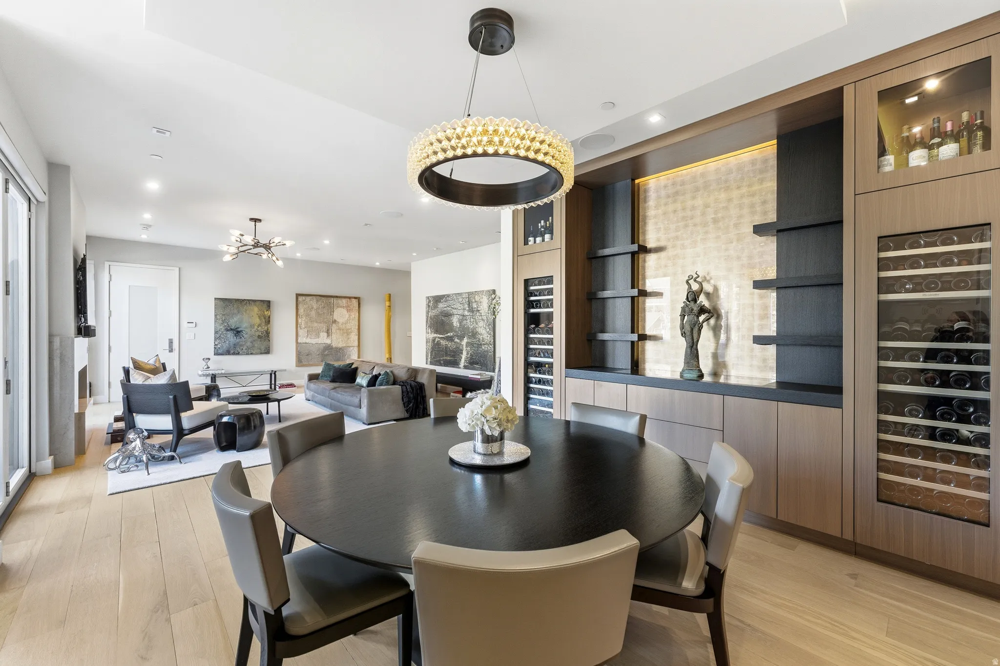 Open-concept living space featuring wood-finish flooring, a built-in beverage storage wall, recessed lighting, and a modern chandelier