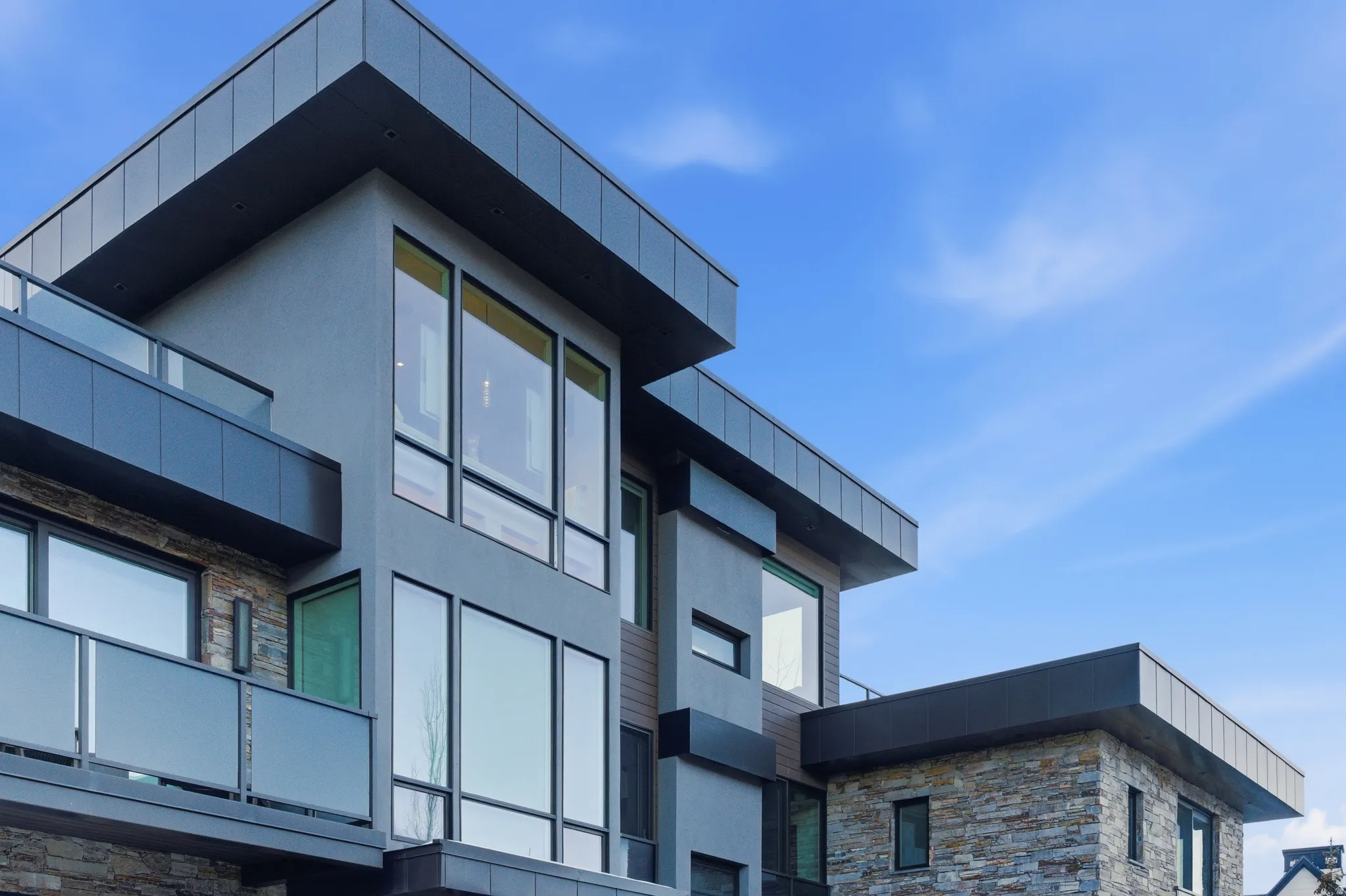 Contemporary multi-level exterior featuring stucco, stacked stone, and vertical wood-finish siding