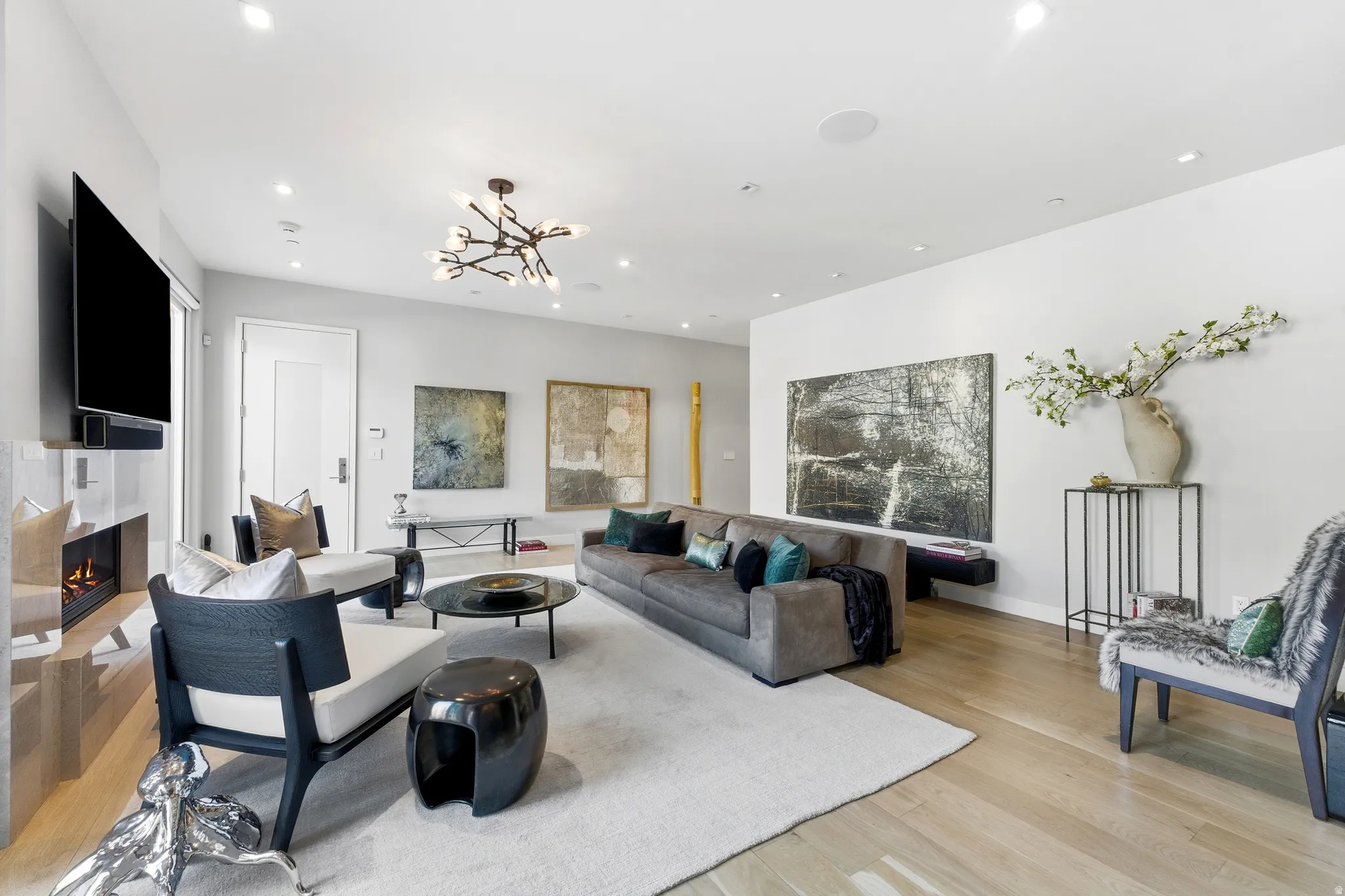 Bright living area with recessed lighting, wood-finish flooring, a built-in fireplace, and a contemporary chandelier