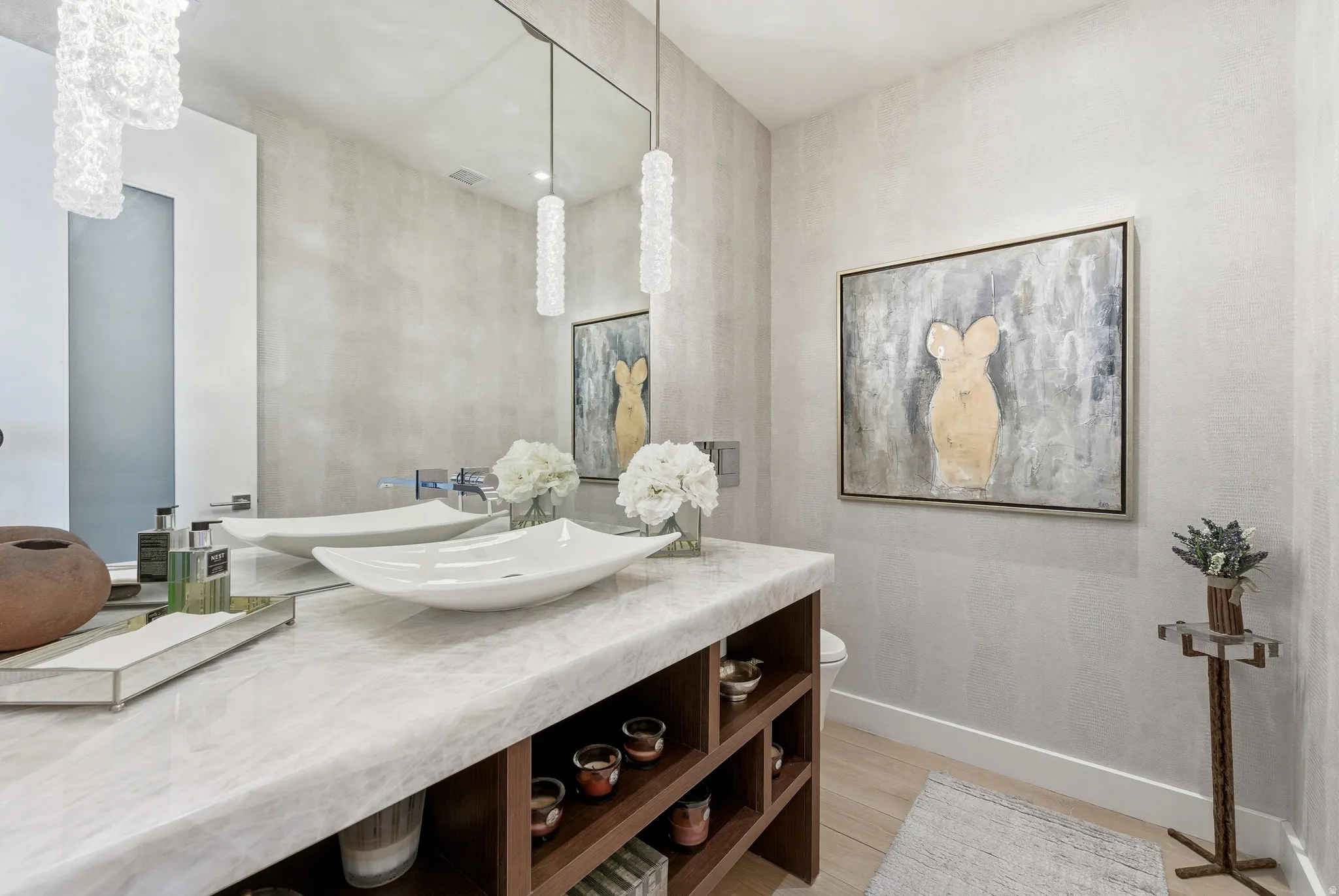 Contemporary vanity featuring a light-toned countertop, dual vessel sinks, and pendant lighting fixtures