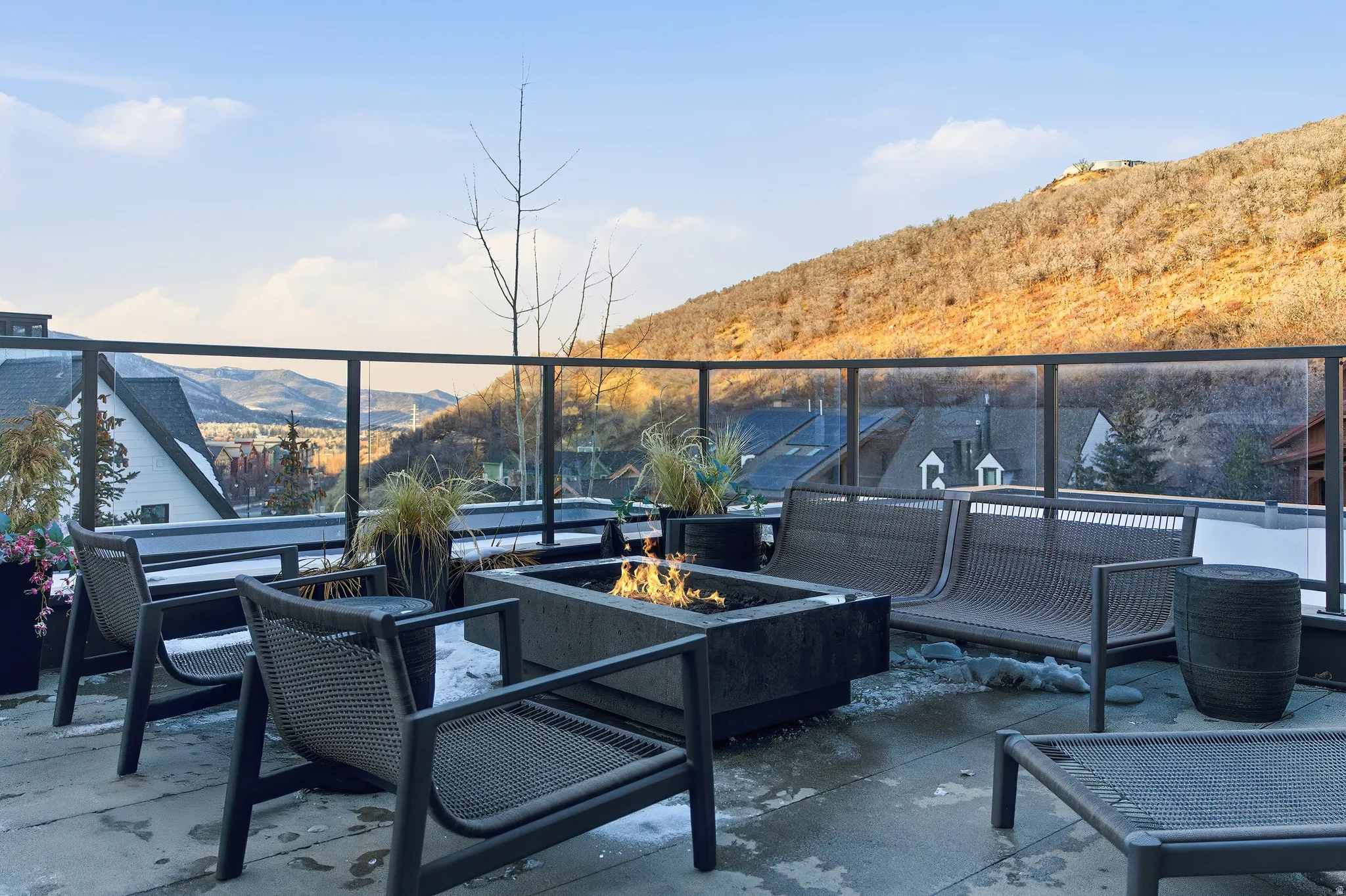 Rooftop patio featuring a glass railing, concrete fire pit, and stone paver flooring