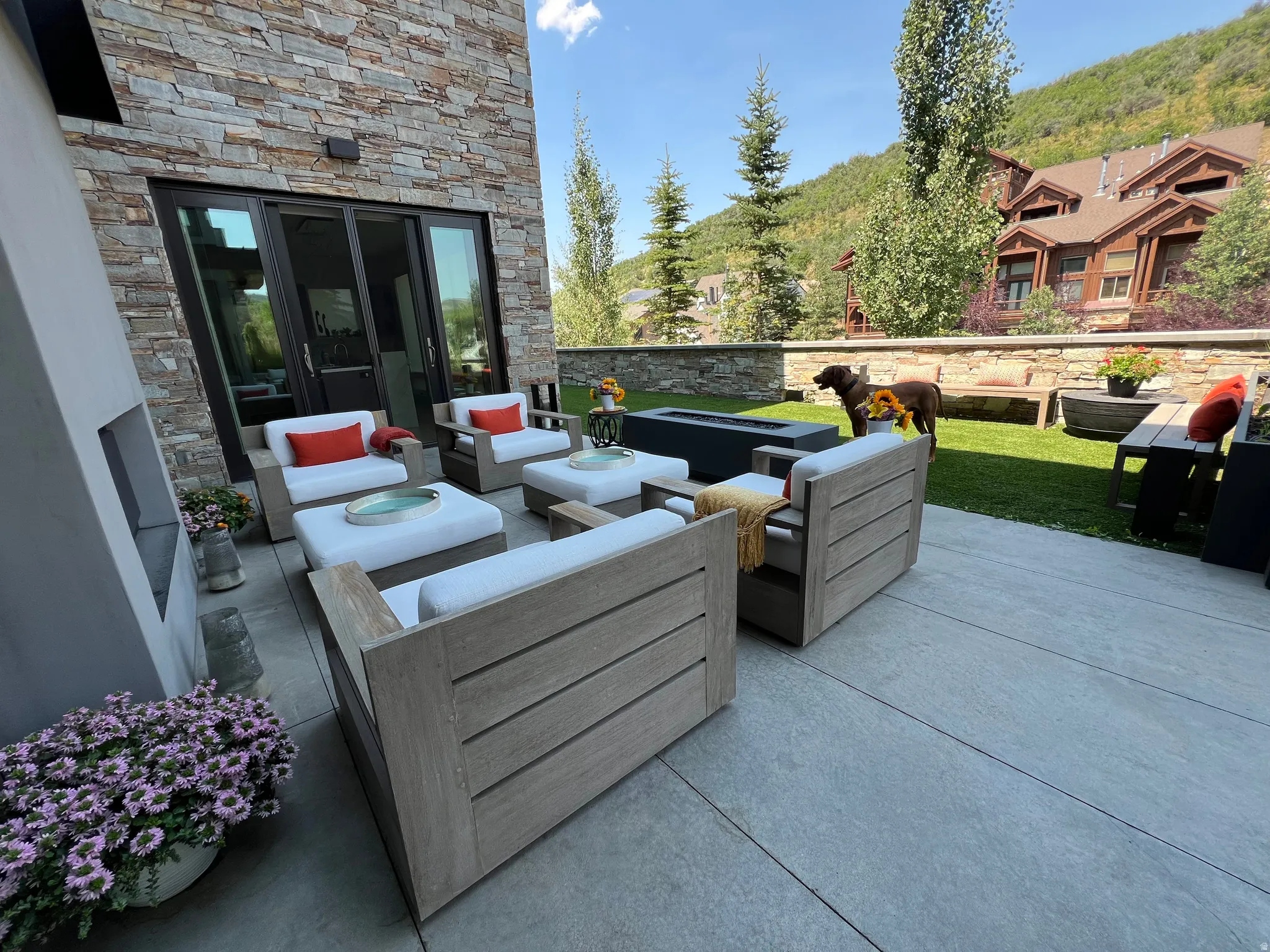 Spacious outdoor patio featuring stone veneer wall, expansive sliding glass doors, and a built-in outdoor fireplace