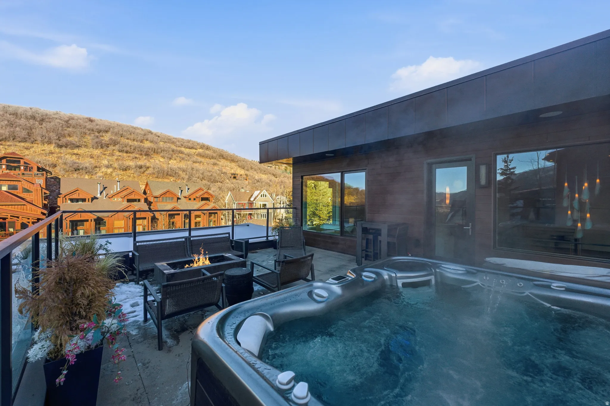 Rooftop terrace featuring a built-in hot tub, linear fire pit, and glass panel railing