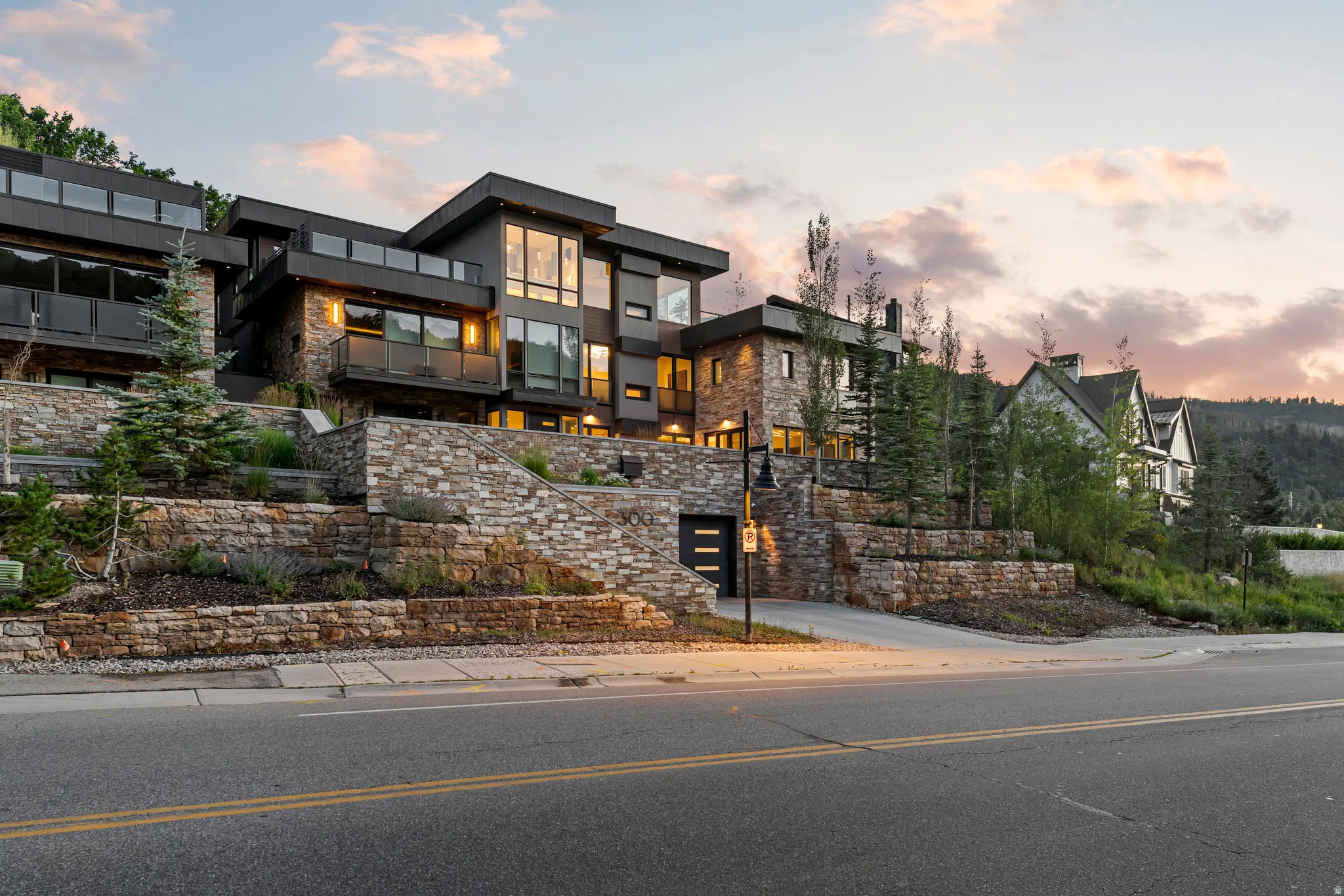 Contemporary multi-level residence featuring expansive windows, private balconies with glass railings, and a stone facade