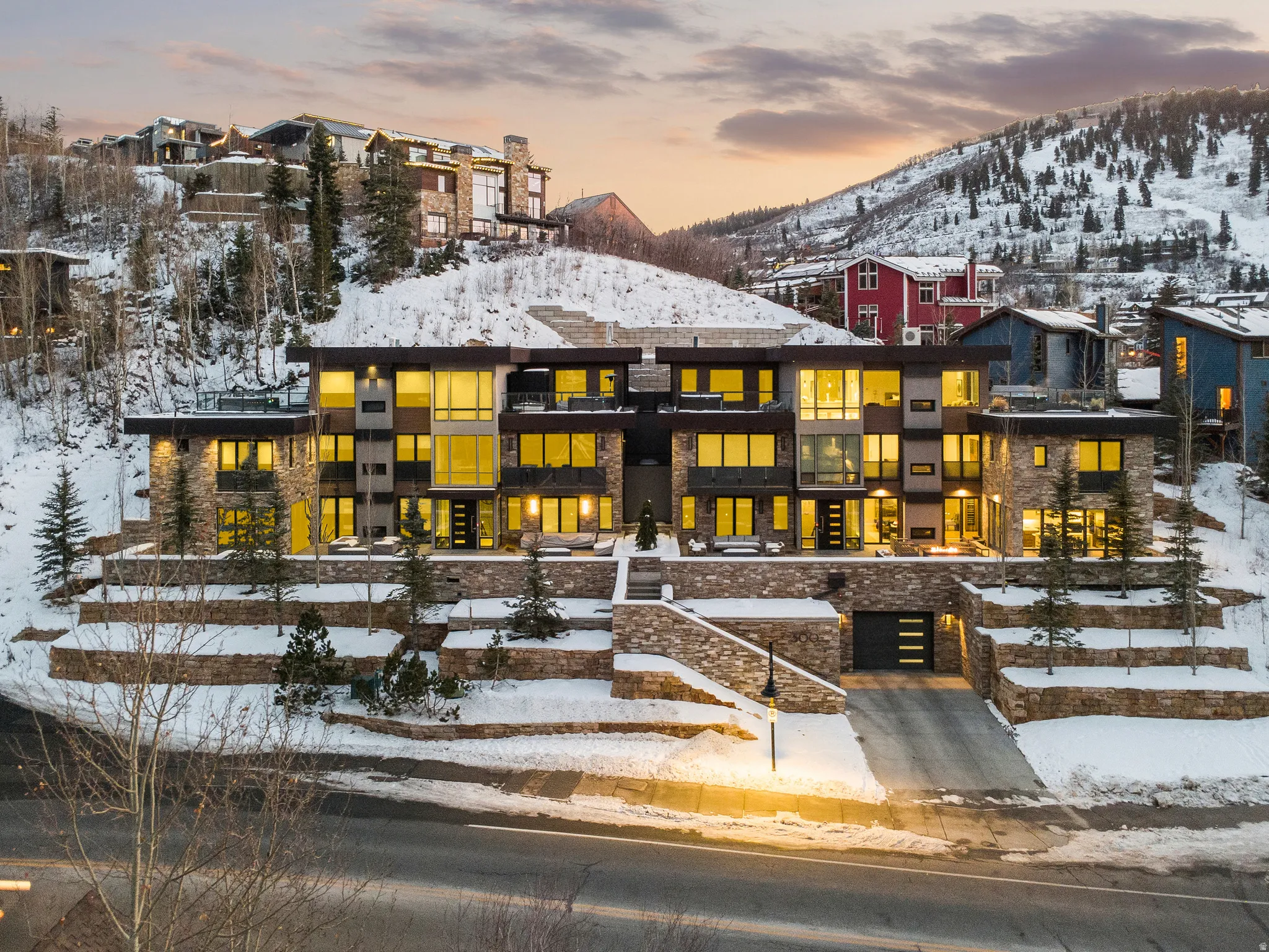 Modern multi-level structure featuring extensive fenestration, stone veneer accents, flat rooflines, and a tiered architectural design