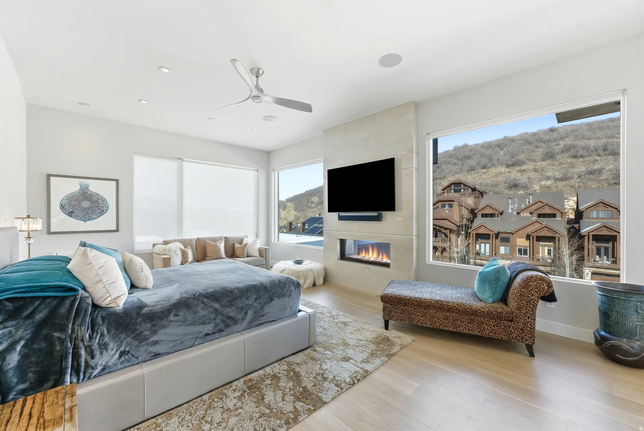 Light wood-finish flooring complements a built-in linear fireplace with a stone surround