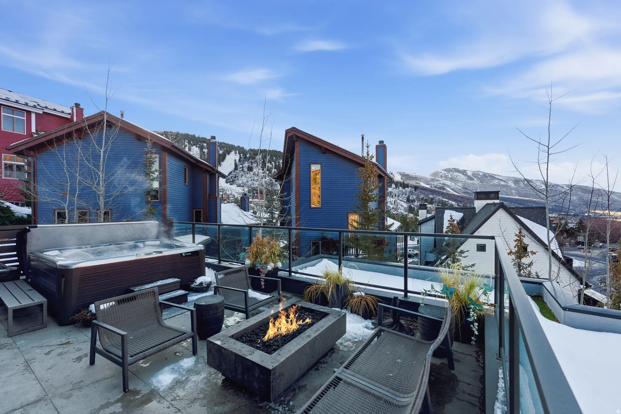 Rooftop terrace featuring a built-in hot tub, concrete fire pit, and glass railing system