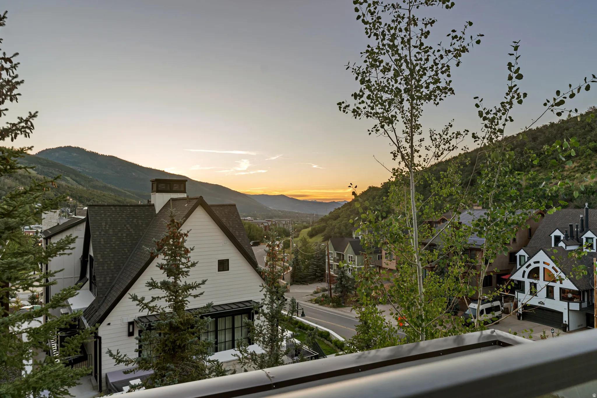 Modern mountain architecture with white siding and dark trim, featuring a prominent chimney structure and gabled roofline