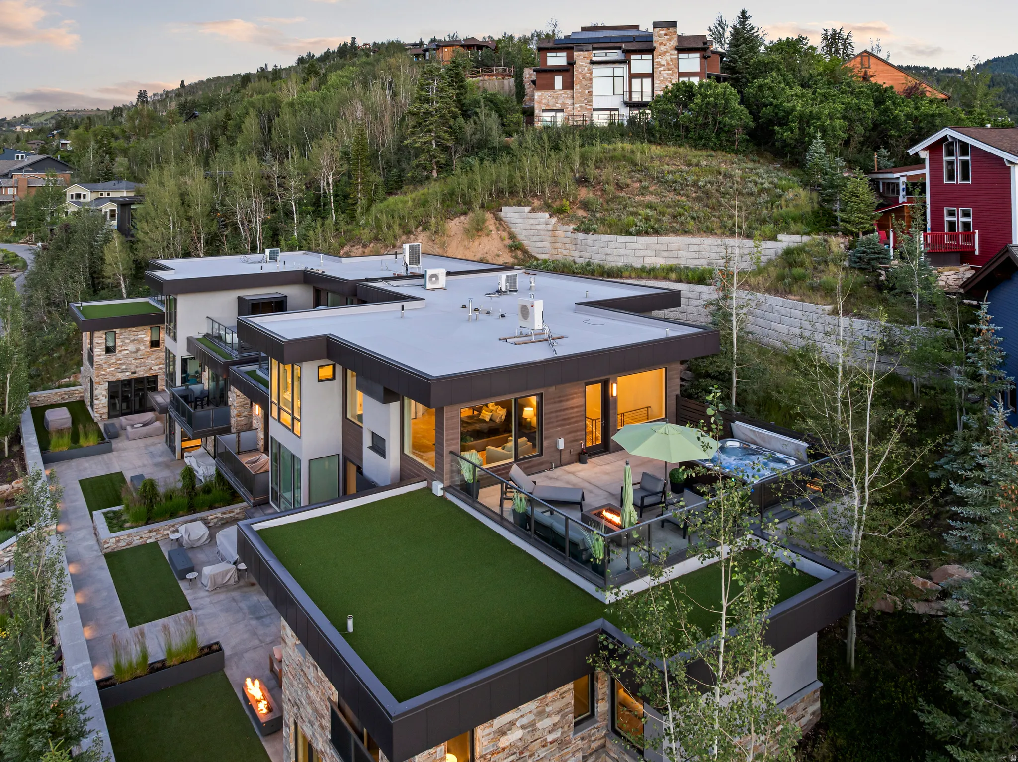 Modern multi-level residence featuring flat roofs, stone cladding, and extensive glass windows
