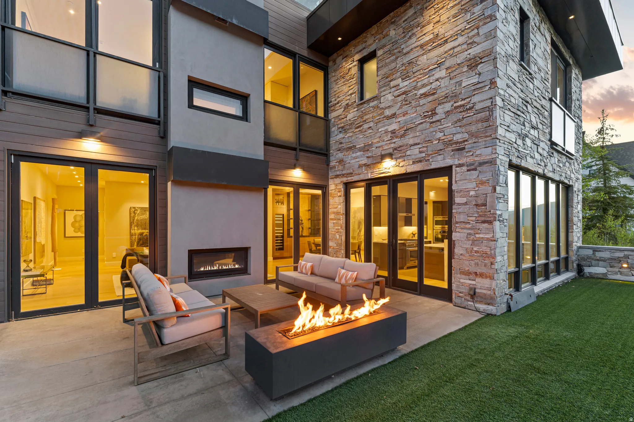 Expansive outdoor patio featuring a built-in fireplace, concrete flooring, and surrounding artificial turf