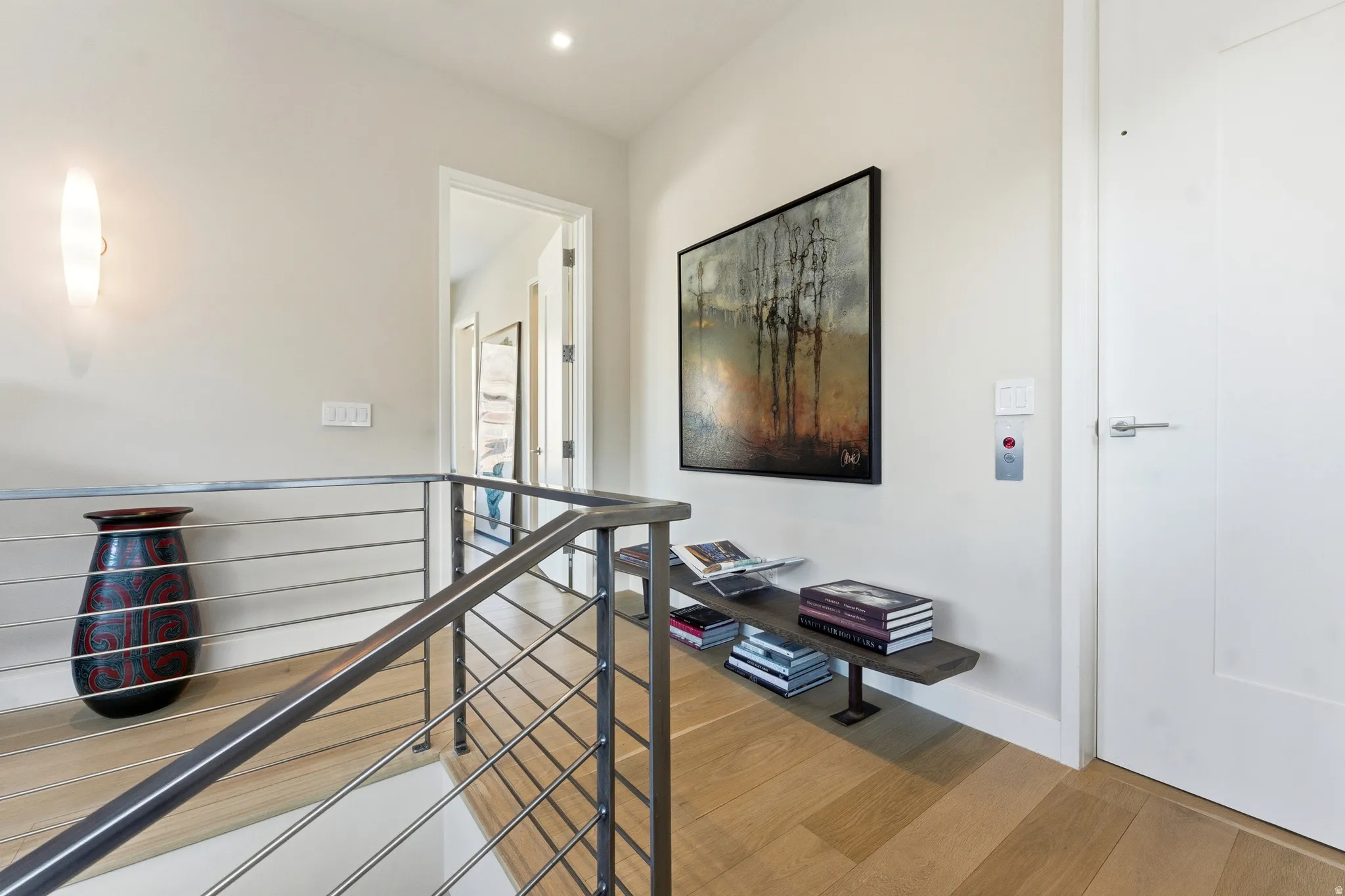 Upper-level landing featuring a contemporary metal and cable railing, recessed lighting, and wood-finish flooring