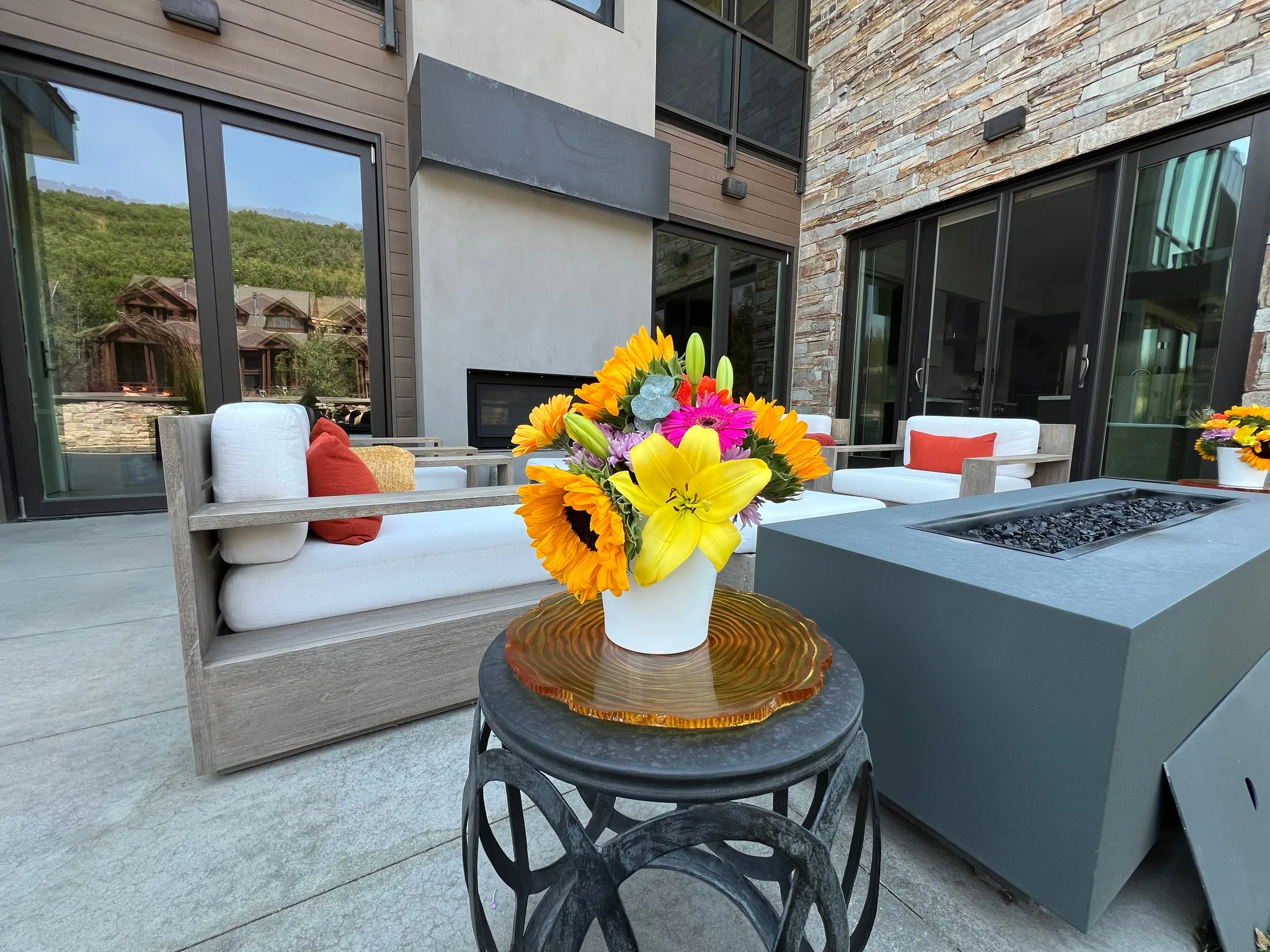 Expansive patio featuring a built-in fire pit, stone accent wall, and multiple floor-to-ceiling glass doors