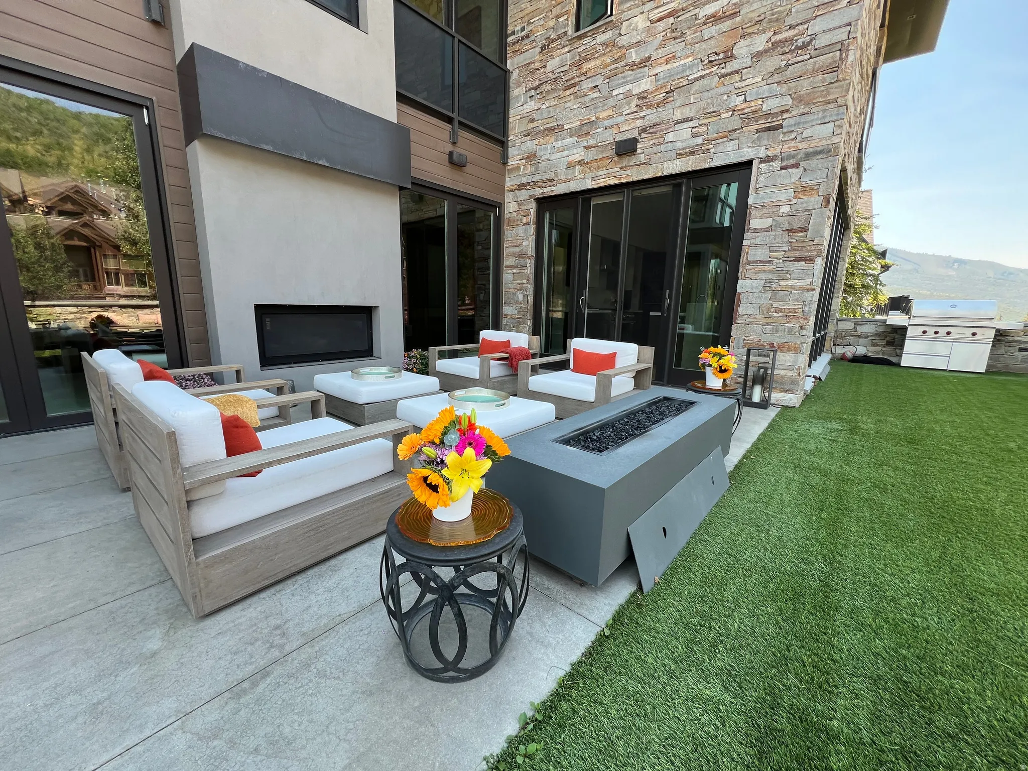 Expansive outdoor patio featuring concrete paving, a built-in outdoor fireplace, and a contemporary fire pit