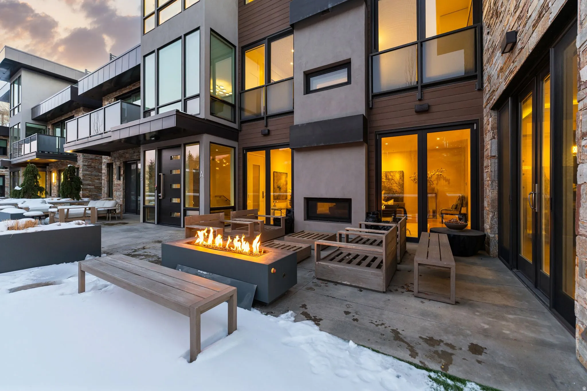 Modern outdoor patio featuring a linear gas fire pit, concrete pavers, and a stone accent wall