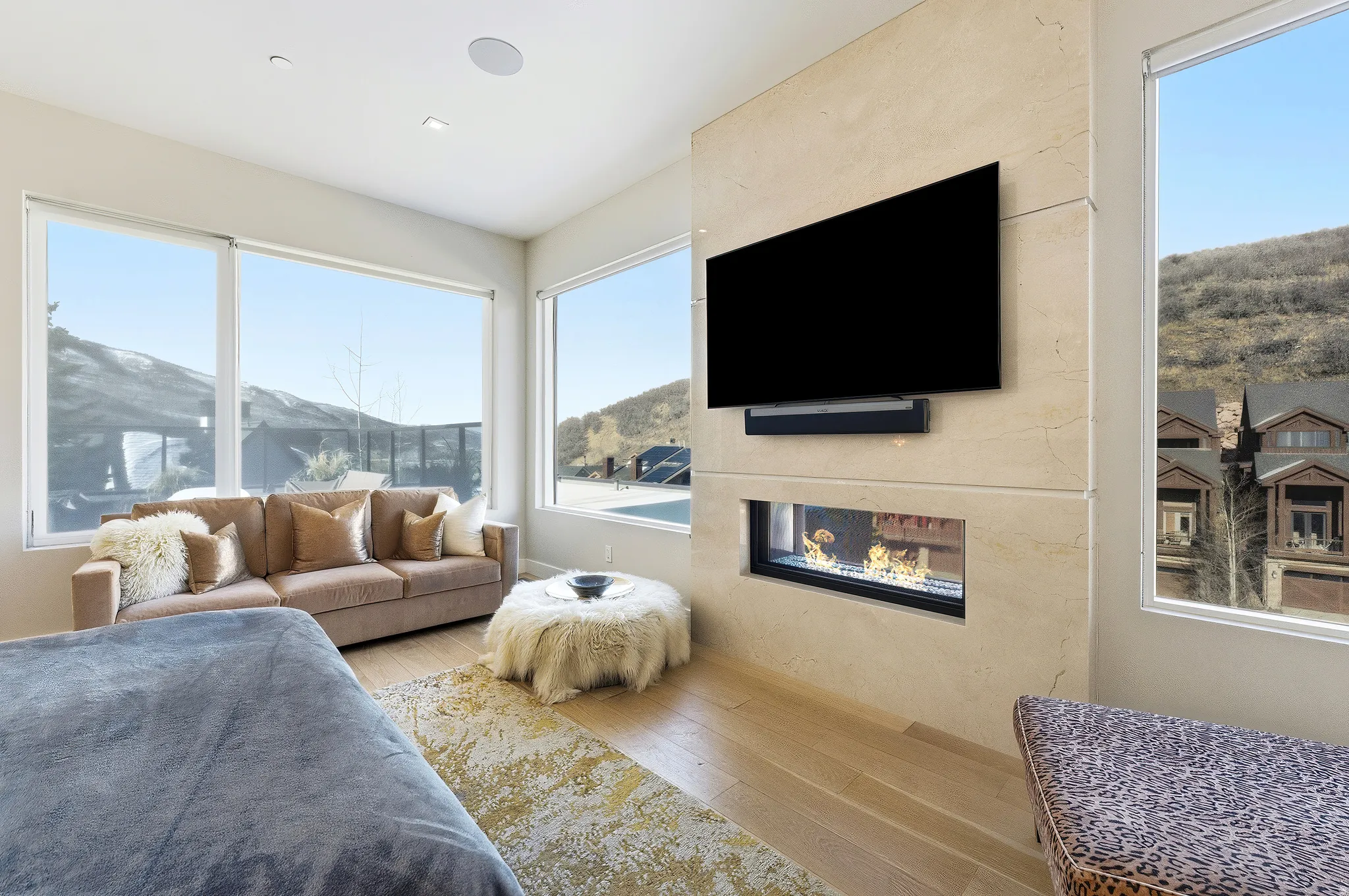 Integrated linear fireplace within a substantial stone-finish wall, featuring a mounted media screen