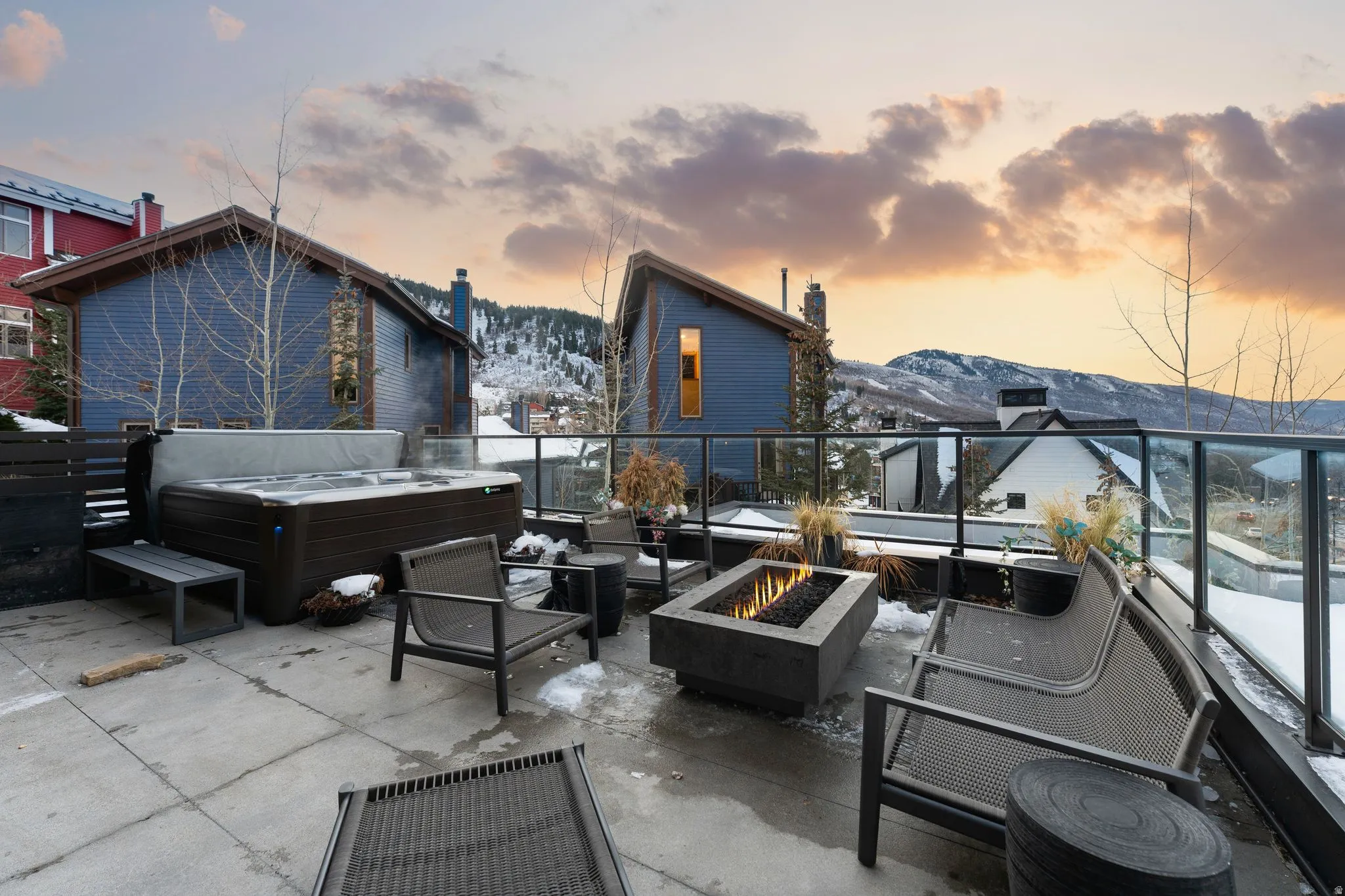 Expansive outdoor patio featuring a hot tub, a built-in fire pit, and a glass-paneled railing