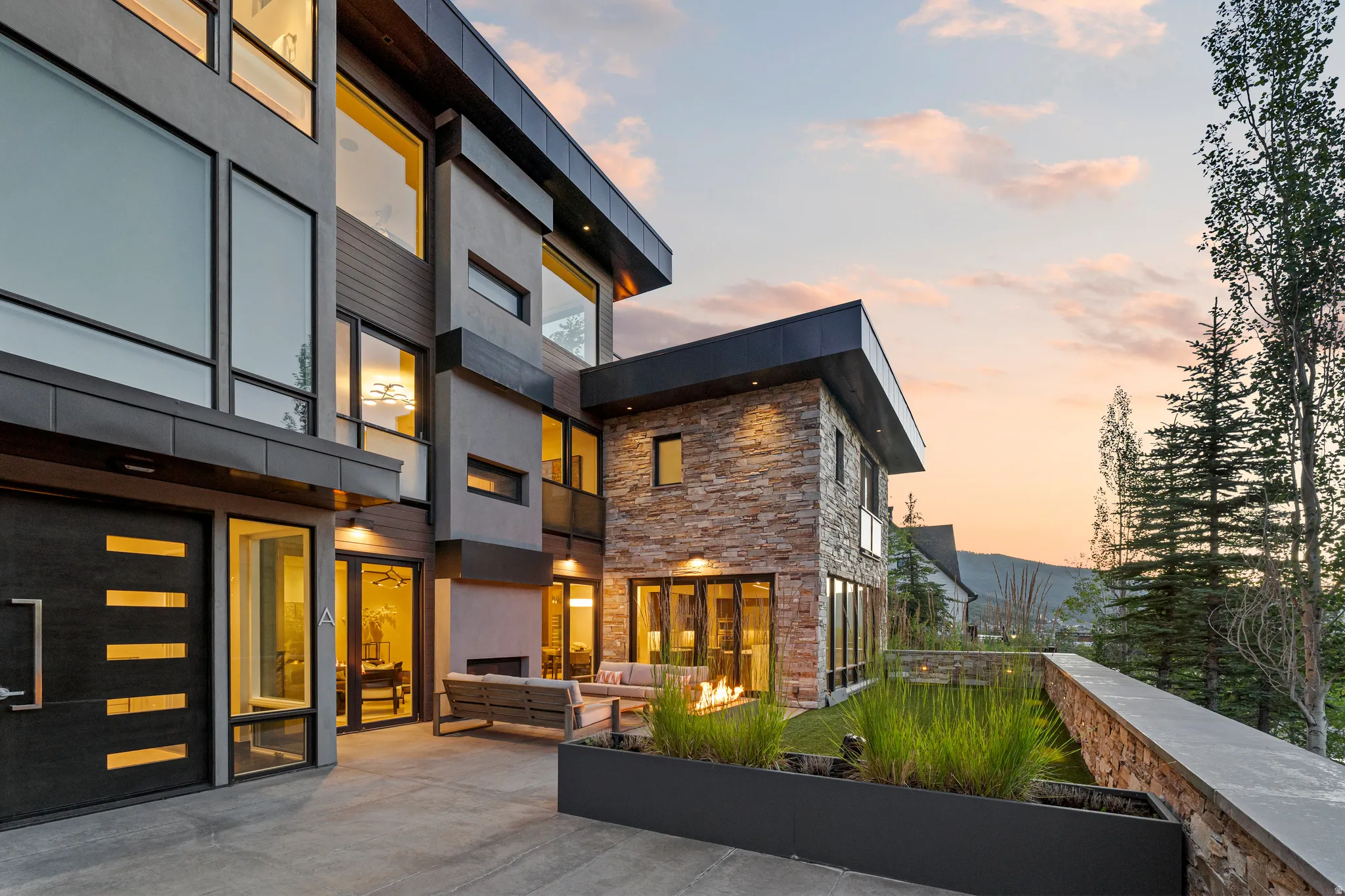 Modern architectural exterior featuring extensive window lines, stone and stucco finishes, and a contemporary entry door