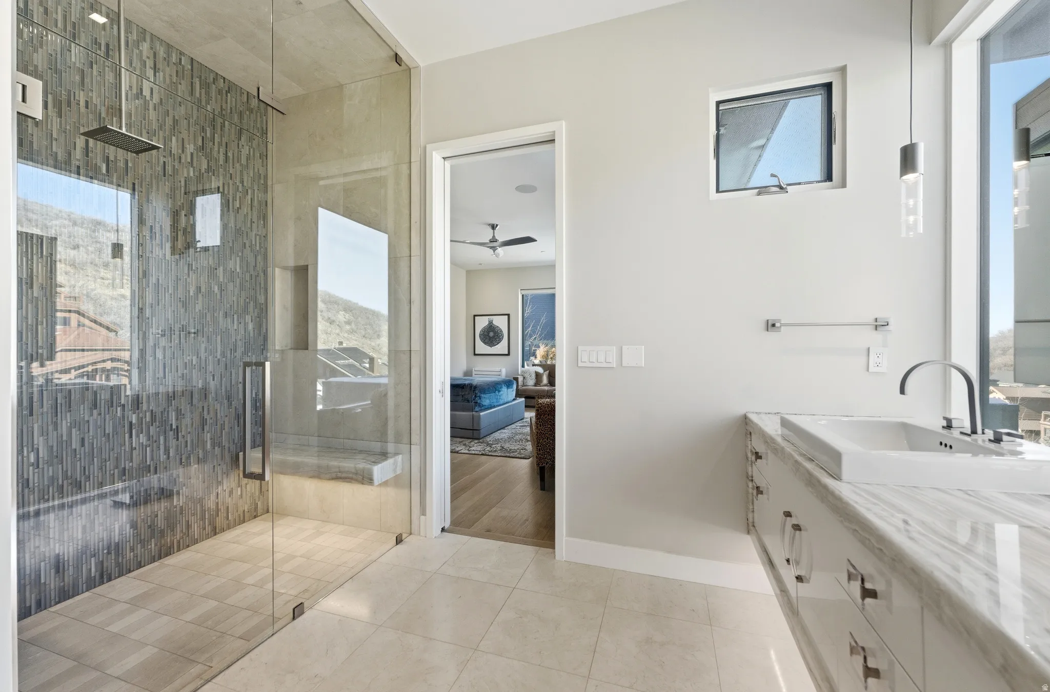 Glass-enclosed shower with stacked stone tile, built-in bench, and rainfall showerhead