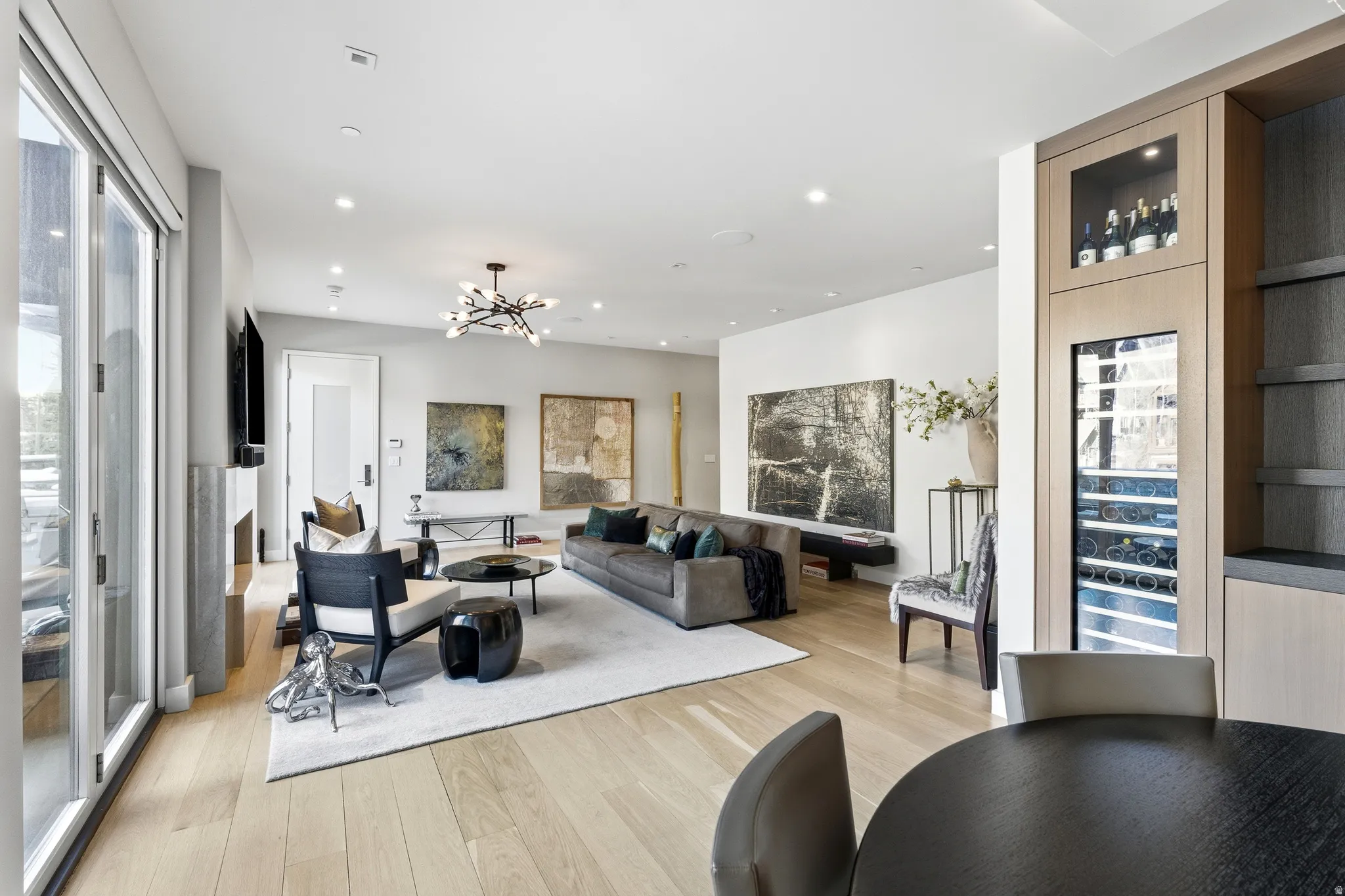 Spacious living area featuring light wood-finish flooring, recessed lighting, and a modern chandelier