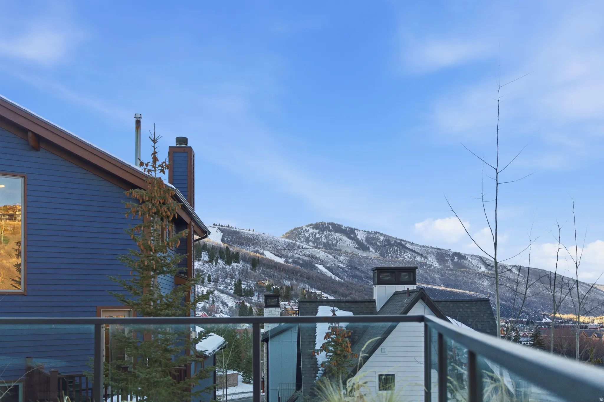 Spacious deck with glass railing offering mountain scenery