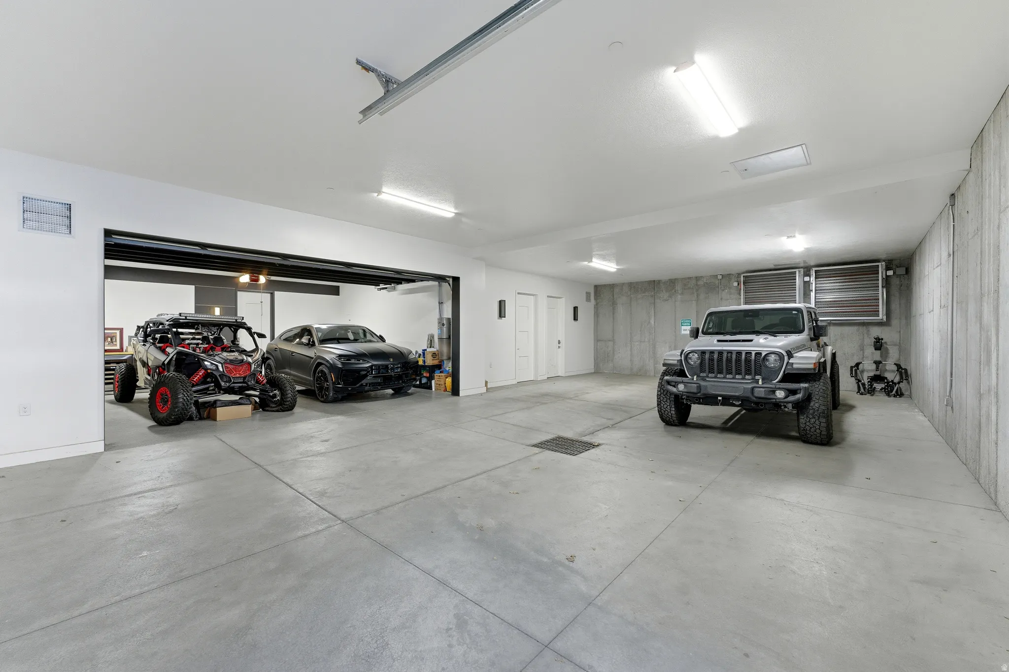 Spacious garage featuring concrete flooring, white walls, and exposed concrete foundation