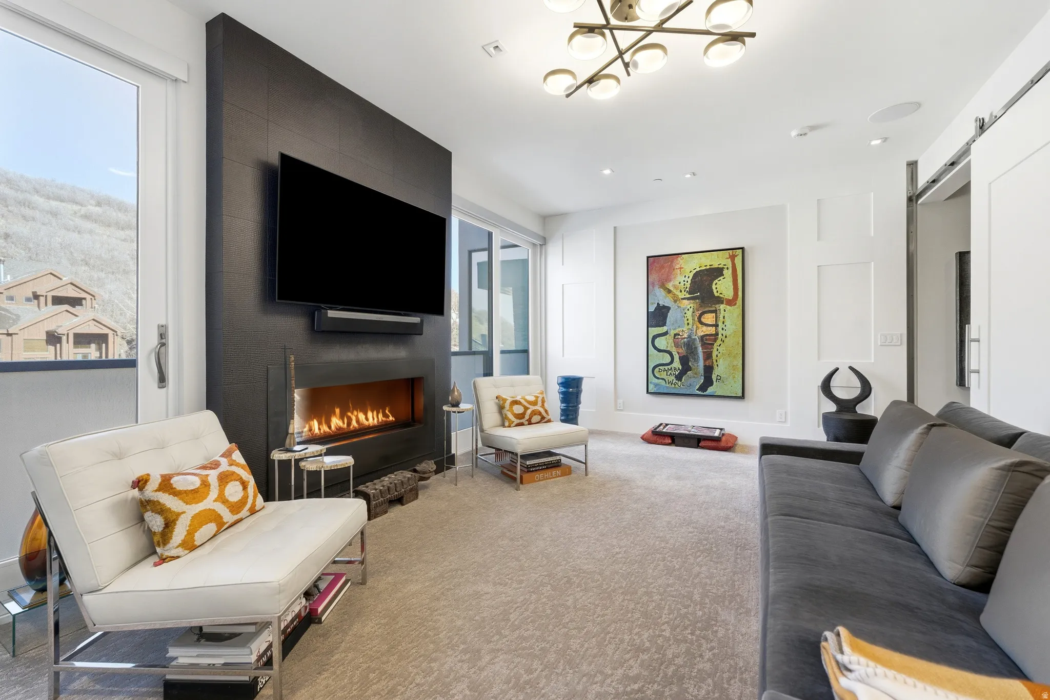 Living area featuring a modern linear fireplace with a dark tile surround, a large wall-mounted display, and a sliding barn door