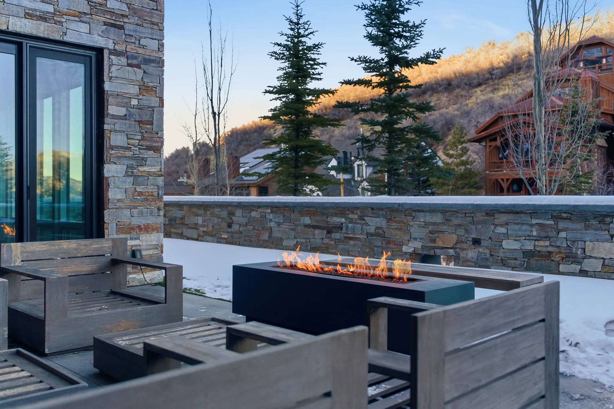 Stone-clad exterior featuring a patio with a linear fire pit
