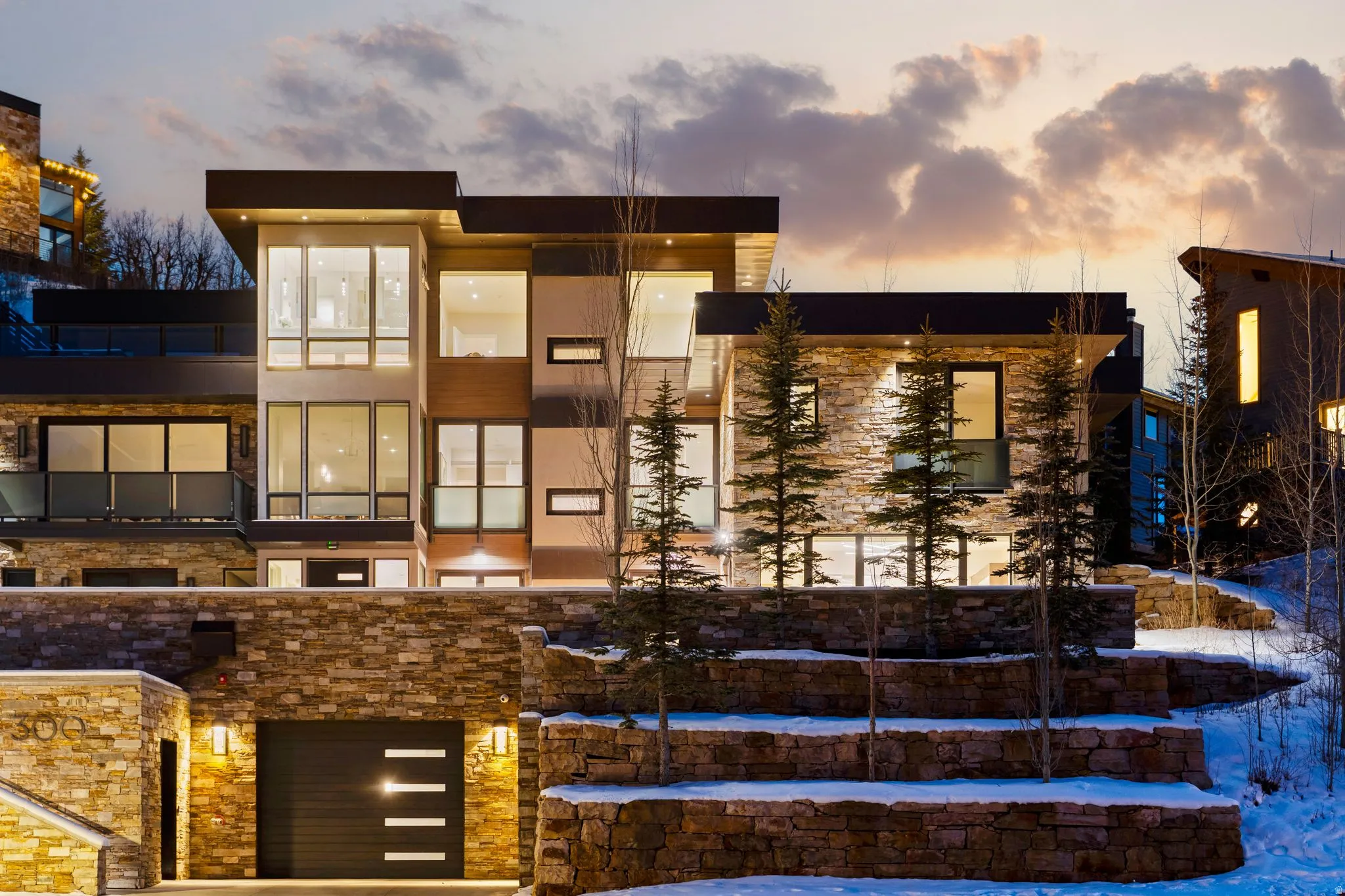 Contemporary multi-level residence featuring extensive stonework and large picture windows