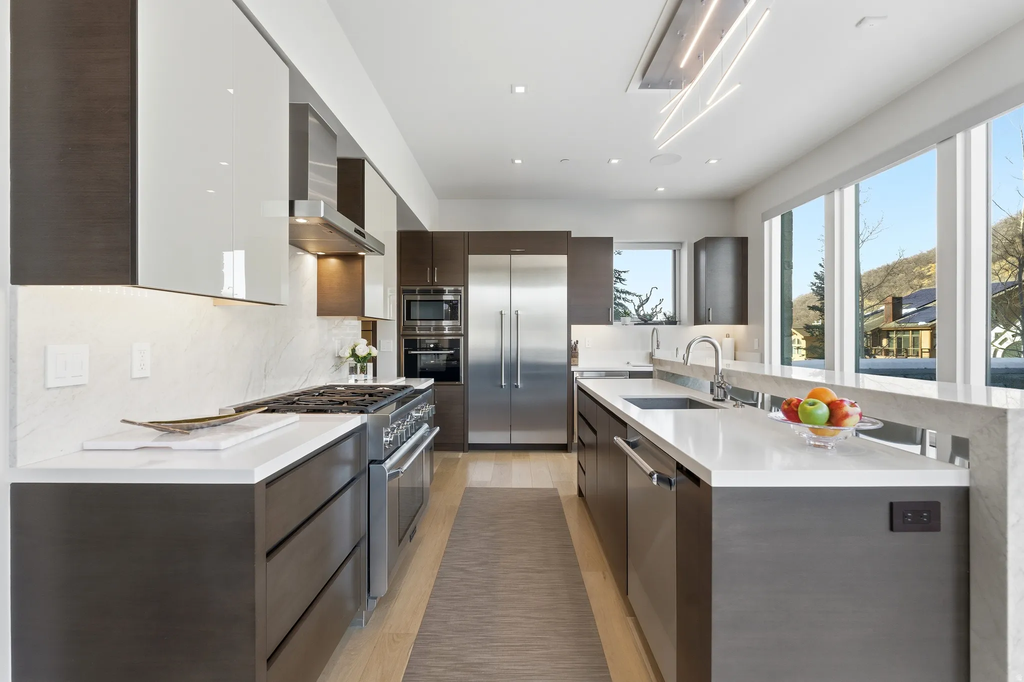Modern kitchen featuring wood-finish lower cabinetry, white upper cabinetry, and a full suite of stainless steel appliances