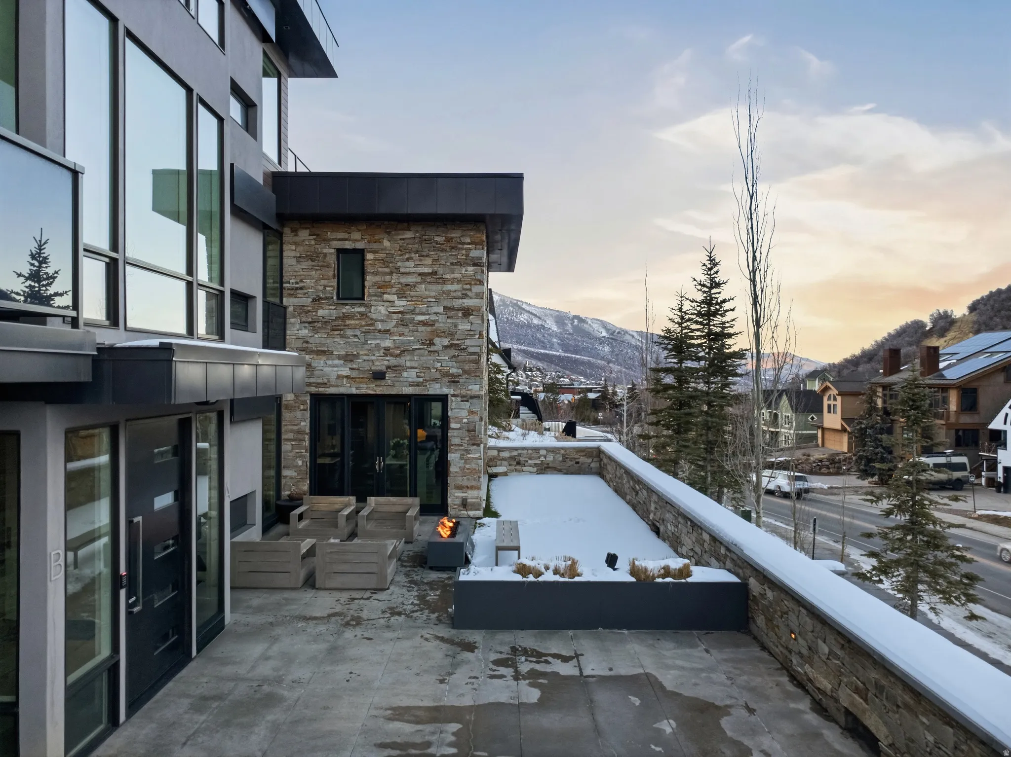 Expansive outdoor patio featuring a fire pit, stone accent walls, and concrete flooring