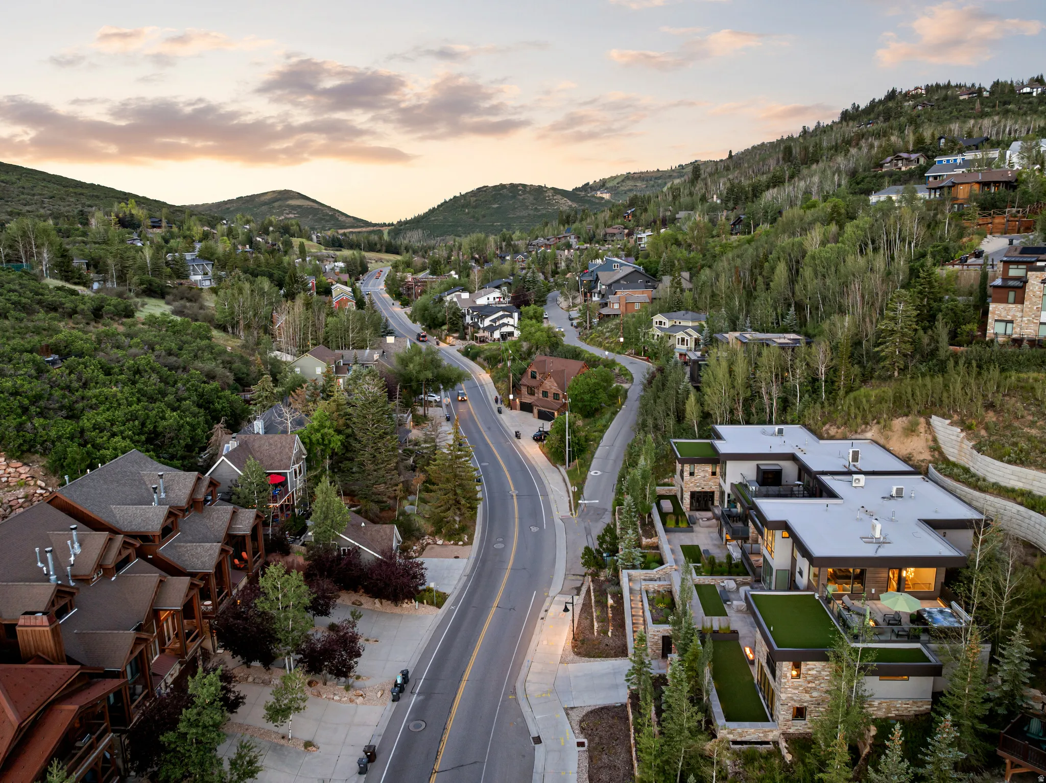 Modern mountain residence featuring a stone and stucco facade, multiple levels of outdoor living space, integrated artificial turf terraces, and a flat roof design