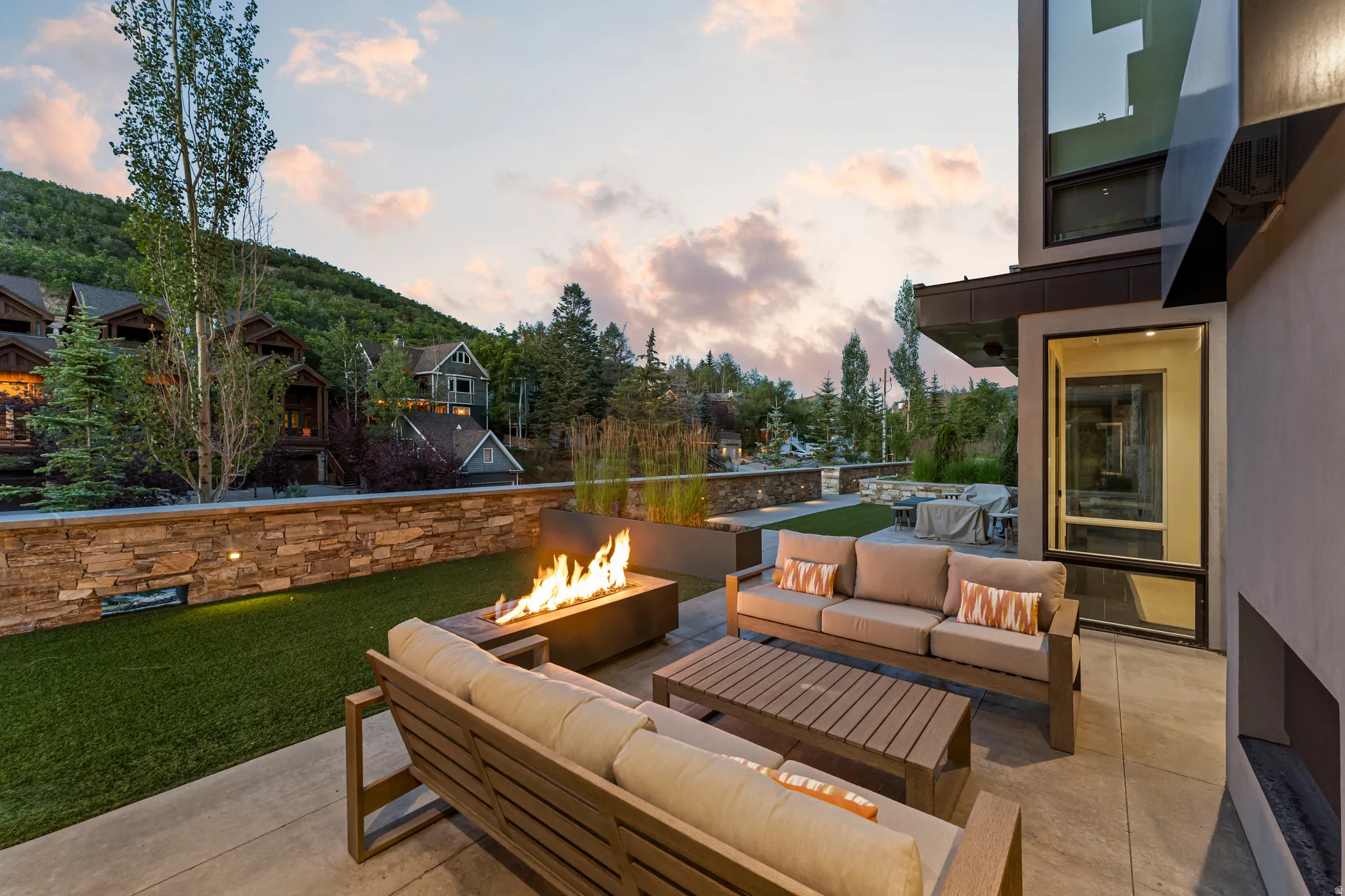 Spacious outdoor patio featuring a built-in fire pit, concrete pavers, and an artificial turf area