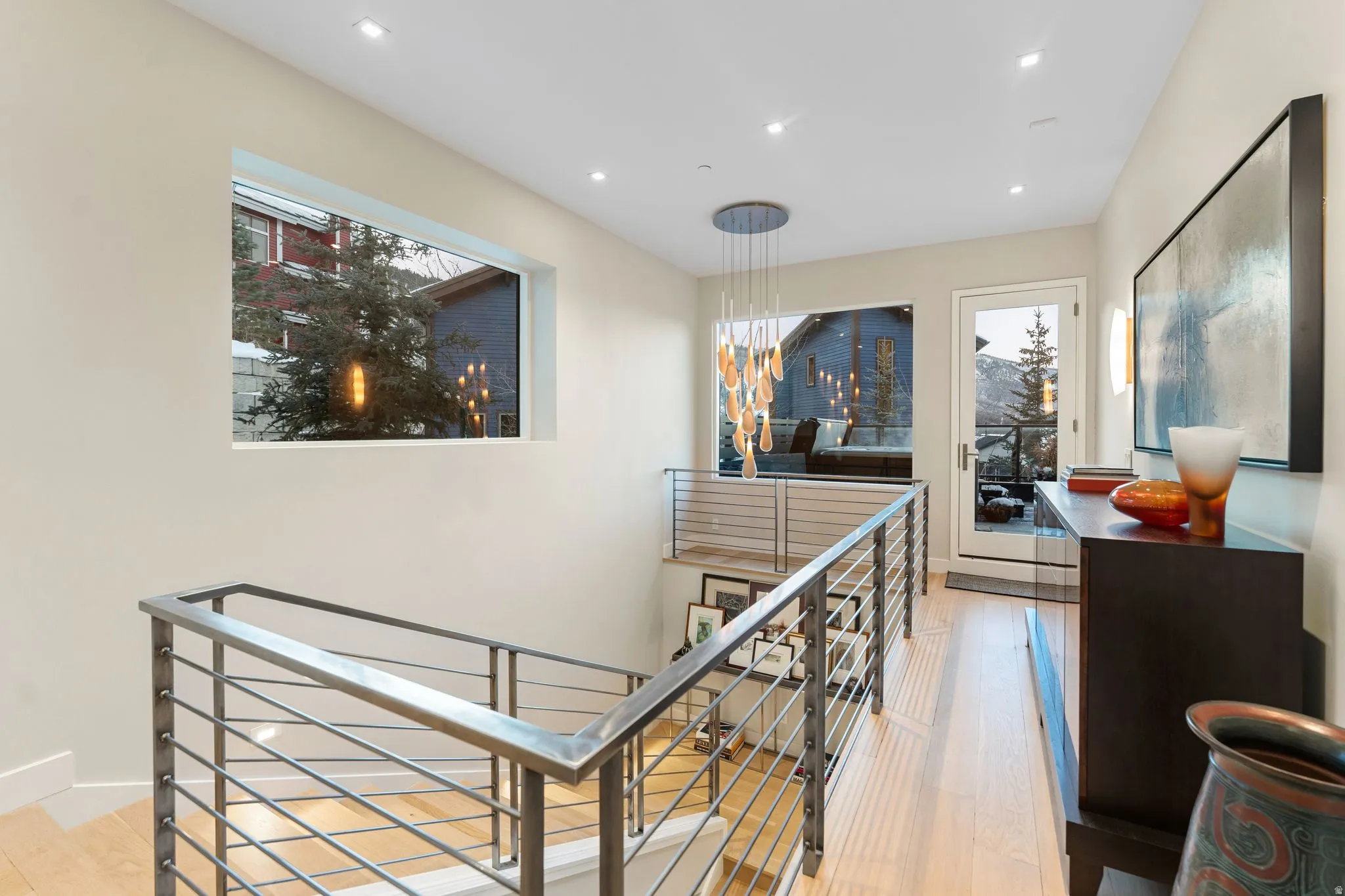 Upper-level landing featuring light wood-finish flooring, recessed lighting, and a modern chandelier